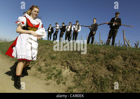 Boys in folk customs carry a giant 'pomlazka' (plated willow stems) to whip girls during traditional celebration of Easter Monday in Nemcicky, South Moravia, on Monday, April 9, 2012. The tradition of whipping girls and women with plaited willow stems and splashing them with cold water should assure Stock Photo
