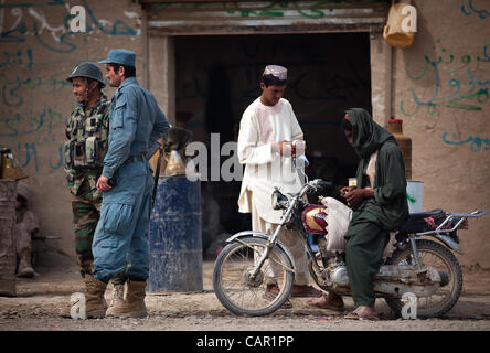 Afghan National Police Lt. Naib (second from left) interacts with an Afghan National Army soldier outside a fuel store in the Hazar Joft Bazaar while manning a vehicle checkpoint here, April 10, 2012. Stock Photo