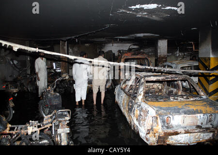 People look burnt vehicles and motorcycles, which were caught fire due to unknown reason, after fire broke out incident in basement of West Land Apartment at Bahadurabad area on early morning in Karachi on Monday, May 07, 2012. Stock Photo