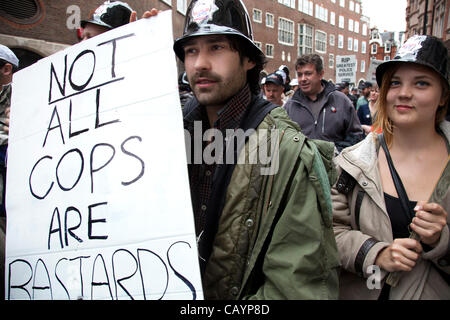 Occupy LSX members in support of the police with a placard reading 'Not all cops are bastards' and wearing plastic police helmets. On a day when 400,000 public sector workers go on strike over cuts, pay and pensions, approximately 30,000 off duty police officers, marched in the capital against proje Stock Photo