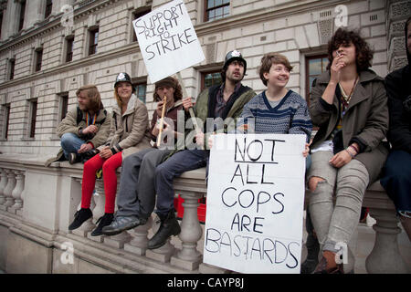 Occupy LSX members in support of the police with a placard reading 'Not all cops are bastards' and wearing plastic police helmets. On a day when 400,000 public sector workers go on strike over cuts, pay and pensions, approximately 30,000 off duty police officers, marched in the capital against proje Stock Photo