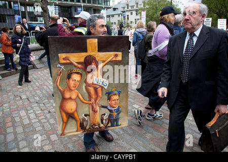 Thursday 10th May 2012. Westminster, London, UK. An Artist holds protest art against NHS cuts depicting David Cameron and Nick Clegg hammering nails into a crucified Jesus figure. Today thousands of public sector workers go on strike over cuts, pay and pensions. Stock Photo