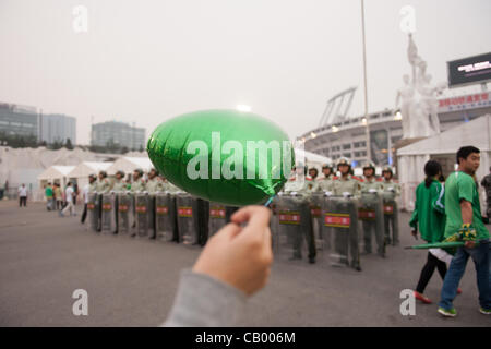 Woman holding a balloon in front of Chinese military police at the Workers' Stadium before the football match between the Beijing Guoan and Guizhou Renhe football teams in Beijing, China, on Friday May 11, 2012. Military police and SWAT teams are routinely present in large numbers to prevent riots a Stock Photo