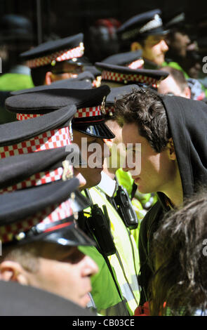Protester and police officer confront each other face to face as the Occupy London anti-capitalist demonstrators move along Fetter Lane. Fetter Lane, London, UK. Saturday 12th May 2012. Stock Photo