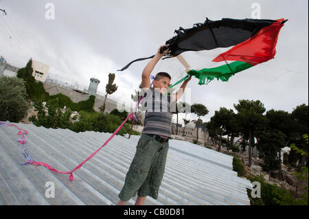 BETHLEHEM, PALESTINIAN TERRITORIES - MAY 14, 2012: In sight of the Israeli separation wall, a boy from Aida Refugee Camp launches a Palestinian flag kite during an event commemorating Nakba Day, the 'catastrophe' experienced by the Palestinian people in 1948. Stock Photo