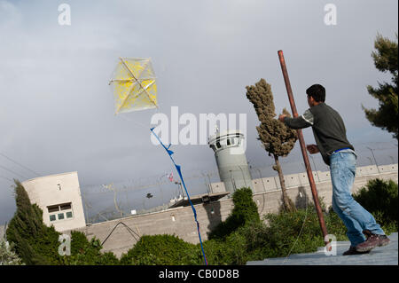 BETHLEHEM, PALESTINIAN TERRITORIES - MAY 14, 2012: A boy from Aida Refugee Camp flies a kite over the Israeli separation wall during a kite festival commemorating Nakba Day, the 'catastrophe' experienced by the Palestinian people in 1948. Stock Photo