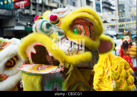 Young boys are clothed in brightly coloured costumes  walking  in a lively procession throw Bangkok street Stock Photo