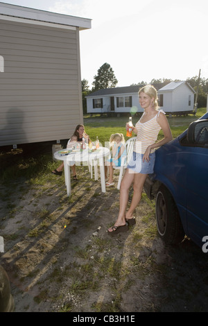 Two women and their children enjoying a cookout in front of trailer home Stock Photo