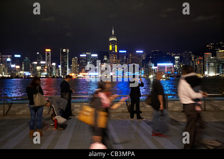 people walk along the avenue of stars with hong kong island and victoria harbour in the background tsim sha tsui kowloon hong ko Stock Photo