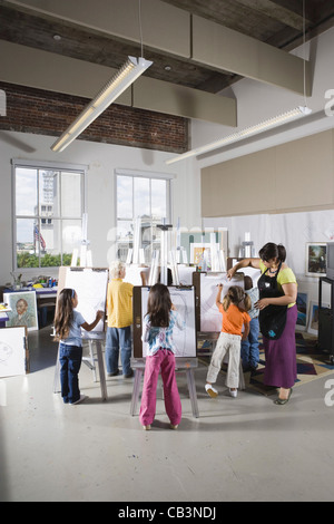 An art teacher with her students drawing on easels in art class Stock Photo