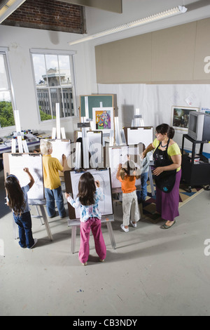 An art teacher with her students drawing on easels in art class Stock Photo