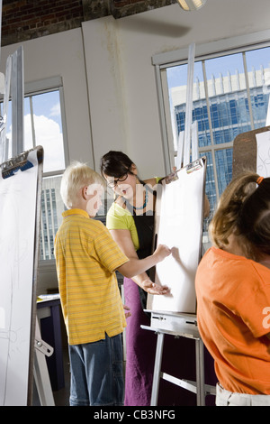 An art teacher with her students drawing on easels in art class Stock Photo