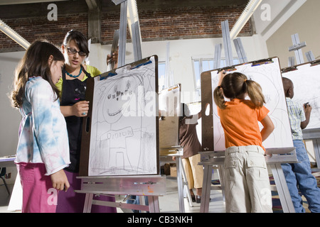 An art teacher with her student drawing on easels in art class Stock Photo