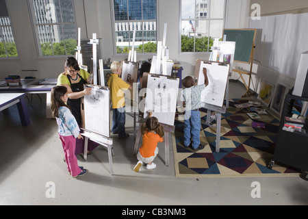 An art teacher with her student drawing on easels in art class Stock Photo