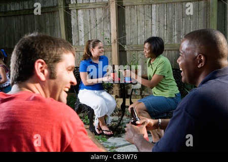 Two couples sitting together on backyard patio, enjoying cold drinks Stock Photo