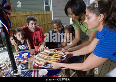 Two families on backyard patio enjoying a cookout on the 4th of July Stock Photo