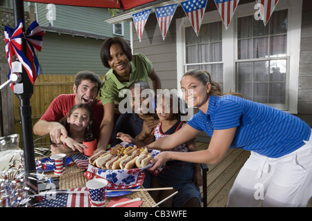 Two families on backyard patio enjoying a cookout on the 4th of July Stock Photo