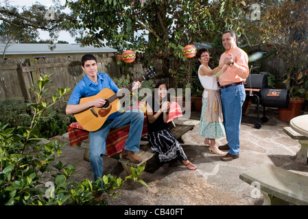 A Mexican-American family playing music and dancing in the backyard of their house Stock Photo