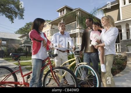 Family with young child conversing with neighbors in front of house Stock Photo