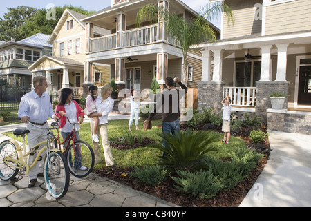 Family with young children conversing with neighbors in front of house Stock Photo