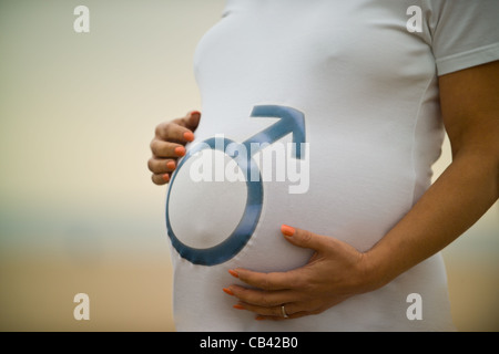 Pregnant woman holding belly wearing tee shirt with male symbol on it. Stock Photo