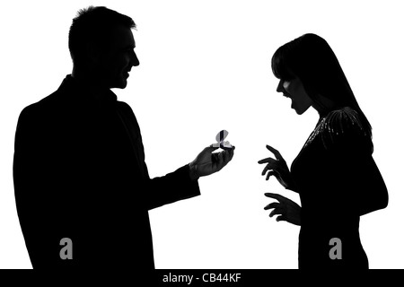 one caucasian couple man offering engagement ring and woman surprised in studio silhouette isolated on white background Stock Photo