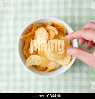 Snacking from the potato chips bowl Stock Photo