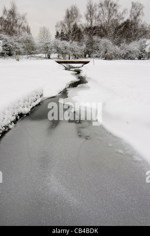 A frozen stream meanders its way through a snow covered golf course Stock Photo