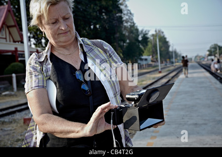 Female photographer with an unusual pellicle mirrored stereo 3D camera rig utilizing two compact cameras. Stock Photo