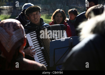 Man plays accordion Sunday afternoon, park Beijing, China, Asia. Chinese gather in groups to sing & play outside Winter sunshine Stock Photo