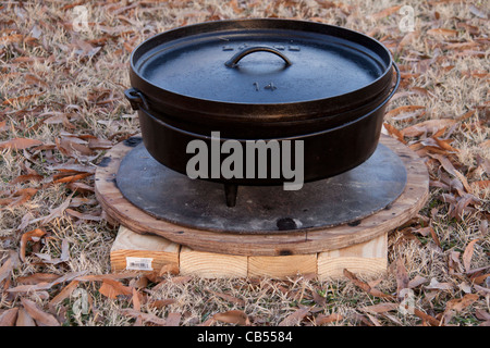 Dutch Oven outdoor cooking cast iron or "black iron" pot with lid and metal support disc. Stock Photo