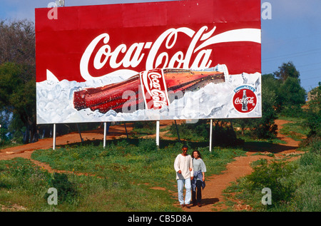 A couple walk past a banner advertising Coca-Cola in Algiers, Algeria. Stock Photo