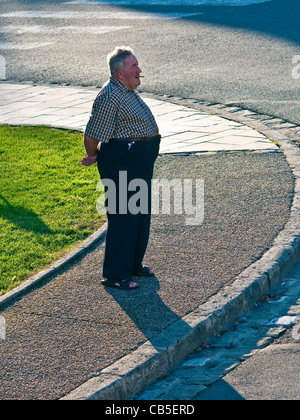 Overhead view overweight man smoking on street corner - France. Stock Photo
