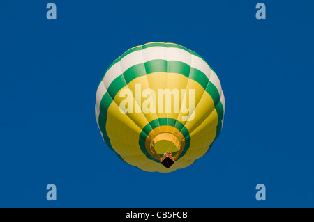 Green, white and yellow hot-air balloon airborne, shot from beneath Stock Photo