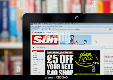 The Sun newspaper website shot against a bookcase background (Editorial use only: print, TV, e-book and editorial website). Stock Photo