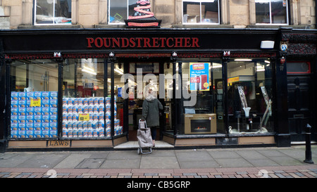 A woman pulling a shopping trolley entering a Poundstretcher store in Hexham Northumberland England UK 2011 Stock Photo