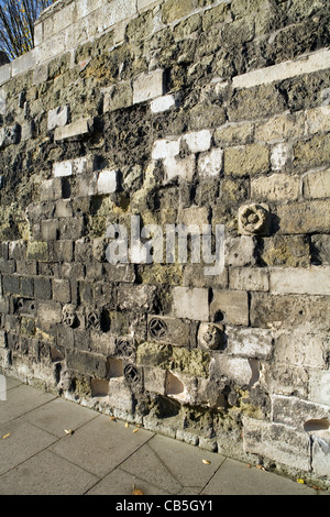 Old stone wall displaying a mix of new, and old weathered stone with small stone carvings Stock Photo