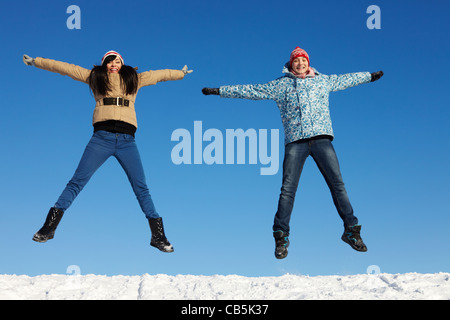 Portrait of happy couple in warm clothes jumping and looking at camera Stock Photo