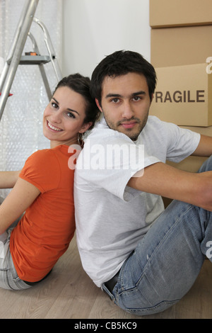Couple sat by ladder and boxes Stock Photo