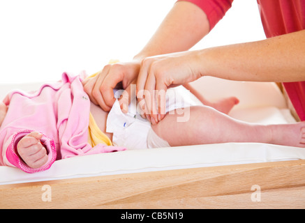 Mother changing child's diaper on nursery table isolated on white Stock Photo