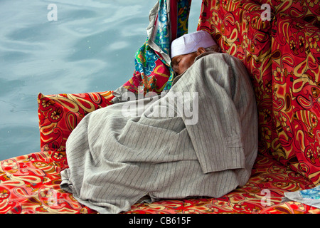 An old man sleeps in a Shikara boat in Dal lake, Kashmir Stock Photo