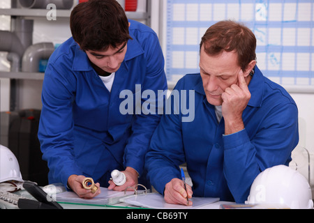 Co-workers checking reference of a piece Stock Photo