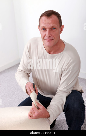 Man knelt by rolled-up carpet Stock Photo