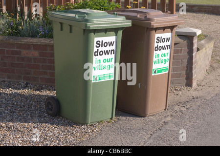 'Slow Down in our Village'; signs attached to local council re-cycling bins. Hickling, Norfolk. Stock Photo