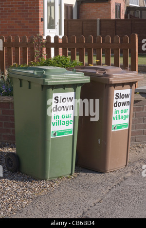 'Slow Down in our Village'; signs attached to local council re-cycling bins. Hickling, Norfolk. Stock Photo