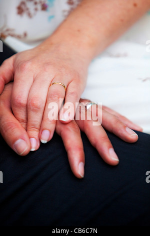 Holding hands of bride and groom with their wedding rings on. Stock Photo