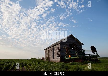 Old storage granary with field disk near bean field in Iowa. Stock Photo