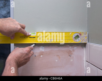 Kitchen tiler using spirit level, Bordon, Hampshire, UK. Stock Photo