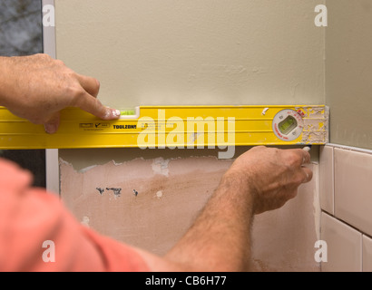 Kitchen tiler using spirit level, Bordon, Hampshire, UK. Stock Photo