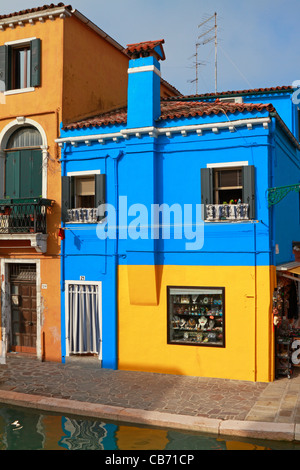 BURANO, ITALY- yellow house with blue shutters and red wooden door ...